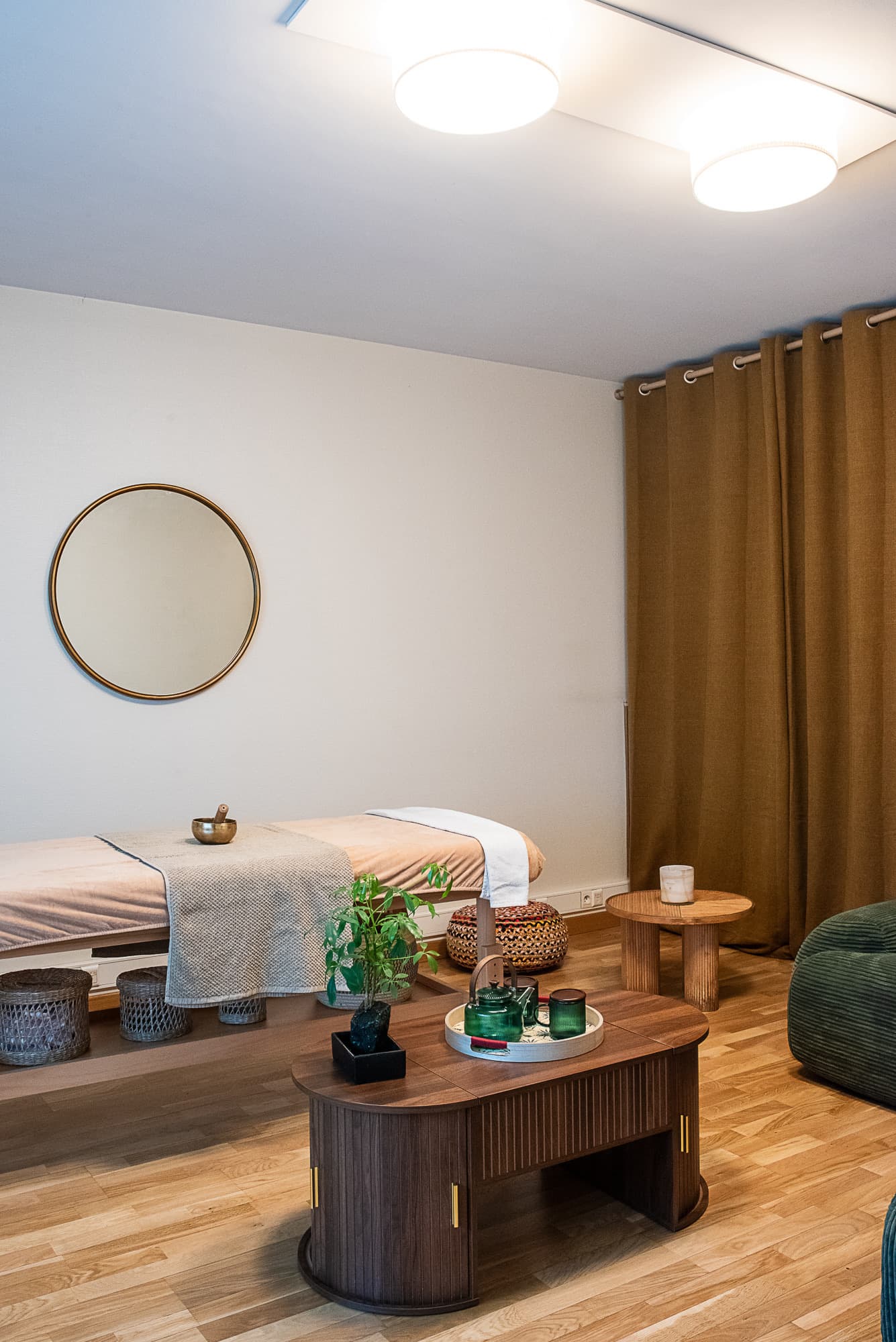 Table de massage sous un miroir doré, bol chantant posé sur le linge